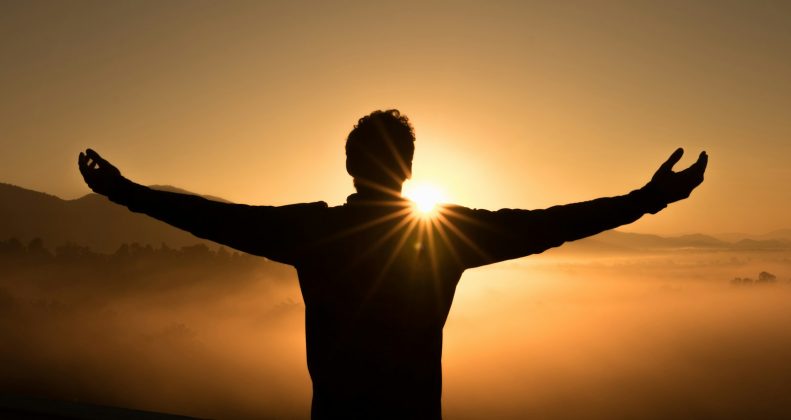 Silhouette of a person on a cliff at sunset